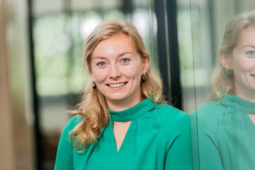 Portret van een lachende vrouw met blond haar en een groene blouse