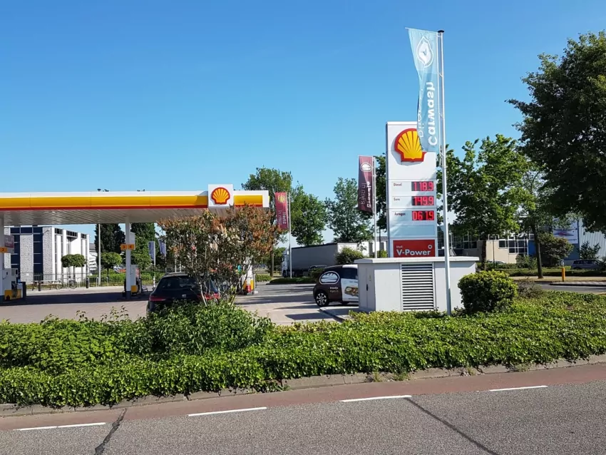 Grijs transformatorstation langs de weg bij een tankstation