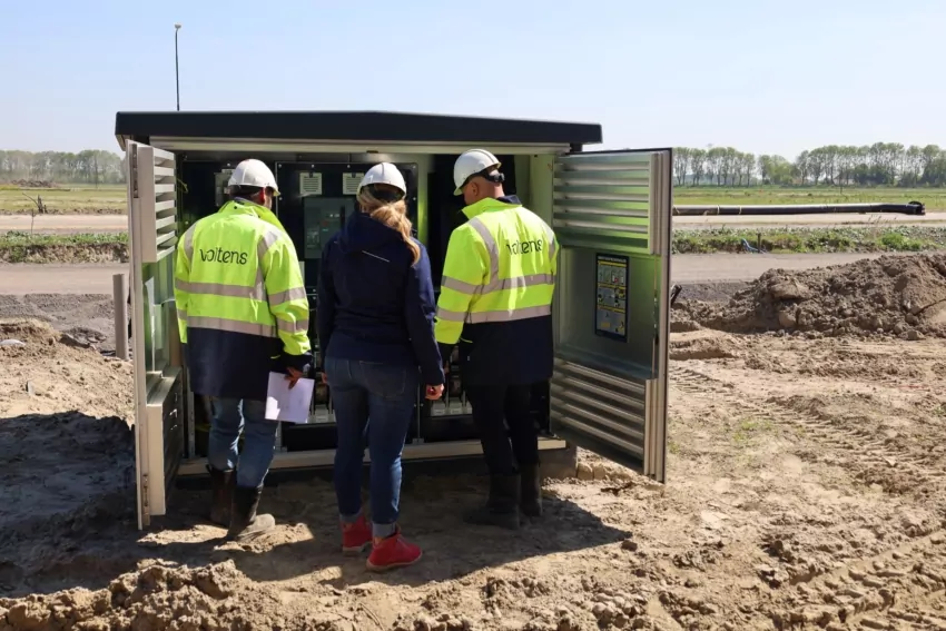 Drie medewerkers bekijken de installatie in een geopend transformatorstation