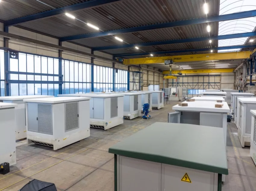 Productiehal met rijen transformatorstations in aanbouw onder een bovenloopkraan
